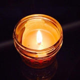 A lit up candle in a glass jar