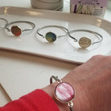 Silver colored stainless  bracelet with a round silver and rosey pink gem on the center