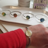 Silver colored stainless bracelet with a round light yellow  gem on the center