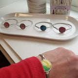Silver colored stainless  bracelet with a round yellow/green gem on the center