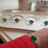 Silver colored stainless  bracelet with a round dark green gem on the center