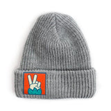 A grey beanie with an orange square patch with an image of a peace hand sign.