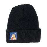 A black beanie with a blue square patch with an image of a cabin.