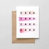 A white card with a black text: "CAKE. CAKE. CAKE. CAKE" and strips of pink watercolors. Comes with a brown envelope.
