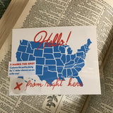 A white postcard with red text: "HELLO FROM RIGHT HERE" and an illustration of map of the US map. Comes with "X" stickers to mark state the card is coming from.