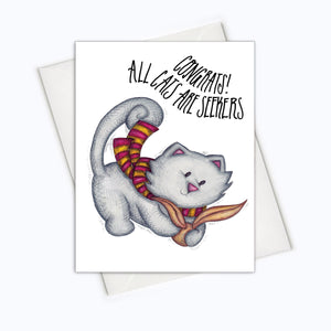 A white card with a black text: "CONGRATS! ALL CATS ARE SEEKERS" and an illustration of a cat wearing the harry potter scarf.  Comes with a white envelope. 