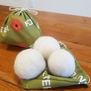 White wool dryer balls in a green fabric bag.