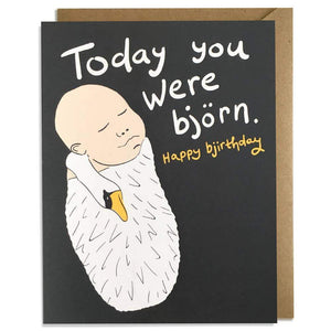 A black card with a text: "TODAY YOU WERE BJORN. HAPPY BIRTHDAY" and an illustration of a baby swaddled in a swan. Comes with a brown envelope.