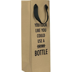 A brown wine gift bag with a black text: "YOU LOOK LIKE YOU COULD USE A DRINK (CROSSED OUT) BOTTLE."