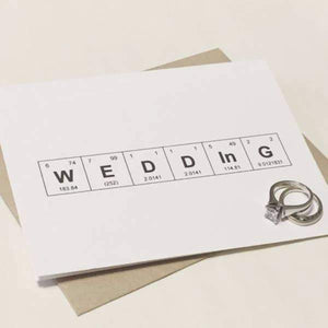 A white card with a black text "WEDDING" in a periodic table design. Comes with a brown envelope.