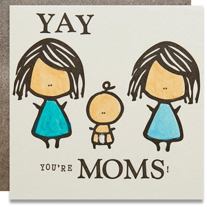 A white square card with a black text: "CONGRATULATIONS YOU'RE MOMS" and an illustration of two moms and a baby.